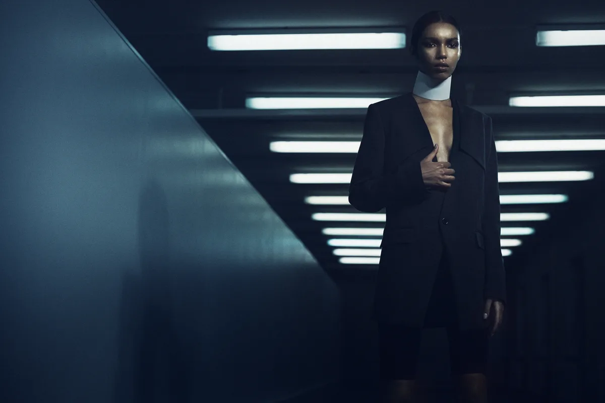 A figure walking down a lit corridor toward the light at its end