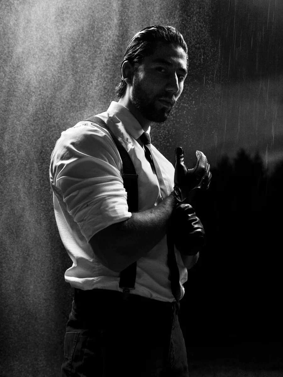 Nicolas Waern in black and white, pulling on gloves in the rain